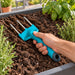 Tridente Chrome Cyrus Company en uso para remover tierra de una jardinera.
